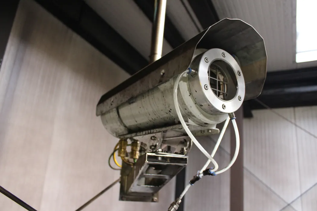 Bild 3:	Die Kameras sind wegen der rauen Umgebungsbedingungen und der potentiell explosiven Atmosphäre in einem Ex-Schutzgehäuse untergebracht; eine integrierte Freiblaseinrichtung hält die Optik permanent staubfrei.(Urheber: Polytec)